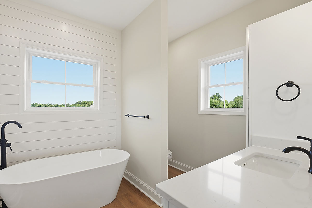 A Del Mar bathroom: a freestanding tub under two windows and shiplap