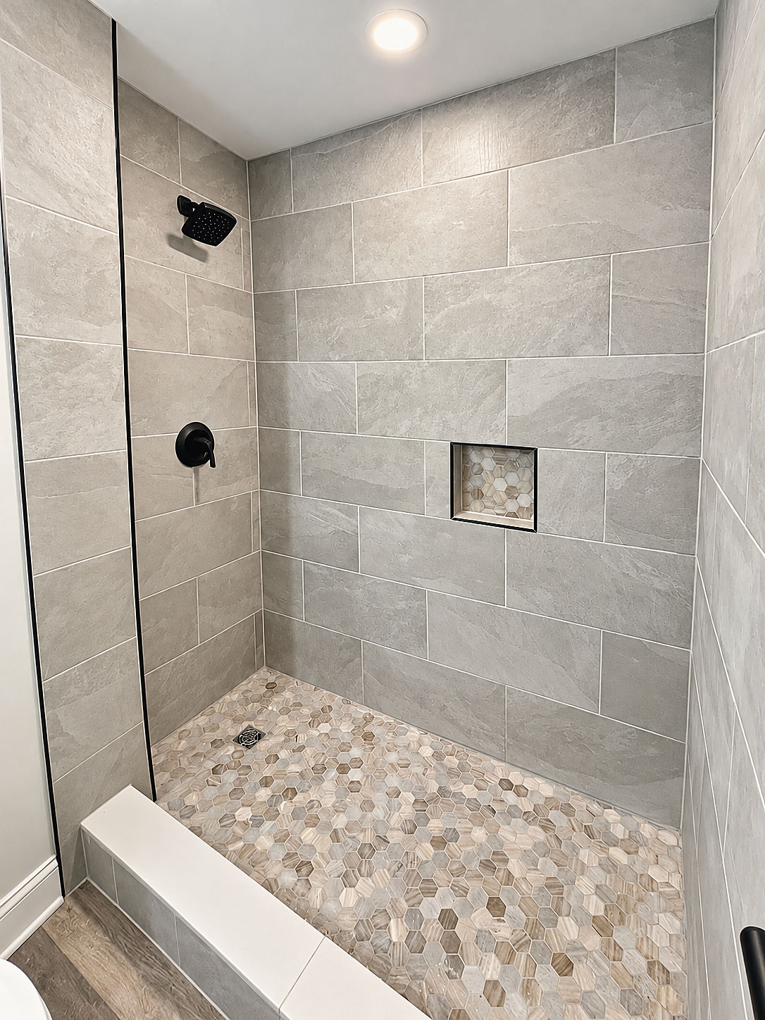 A Del Mar bathroom: a gray tile shower with a niche