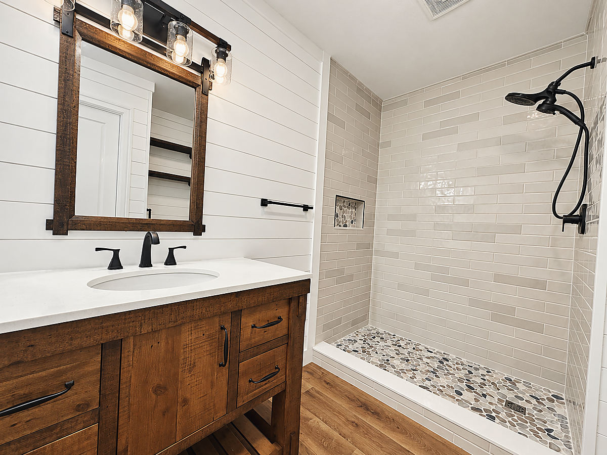 A Del Mar bathroom: a vanity with black fixtures and a tiled shower