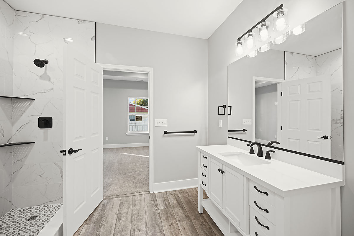 A Del Mar bathroom: a tub with marble-look tile and black fixtures