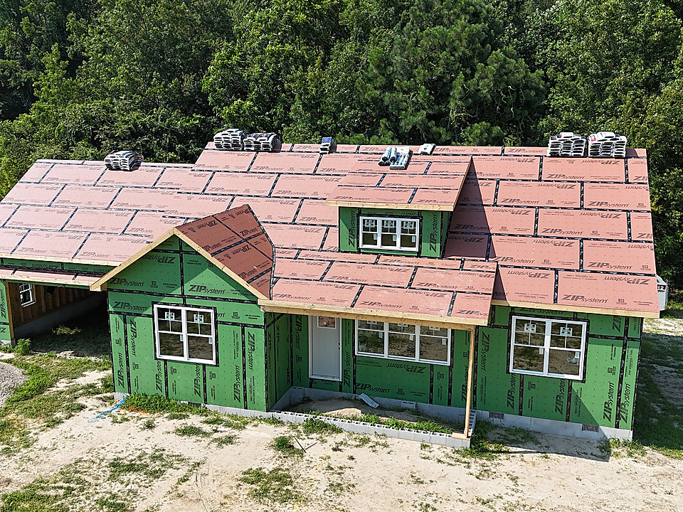 A house being rebuilt with green ZIP sheathing and red roof underlayment