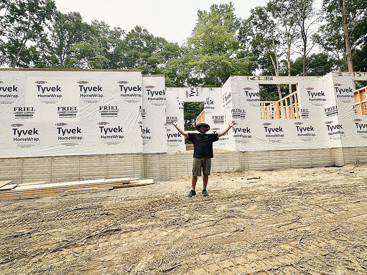 Dale Hunter, arms out, in front of a house framed and wrapped