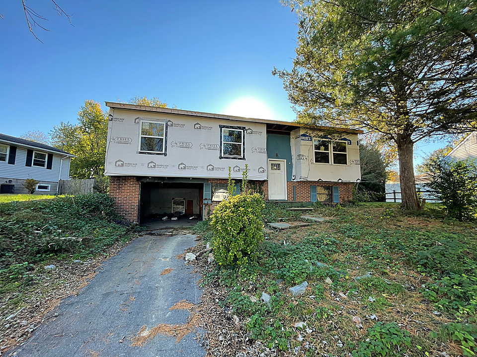 Before: a raised ranch with torn house wrap, an open garage and an overgrown yard