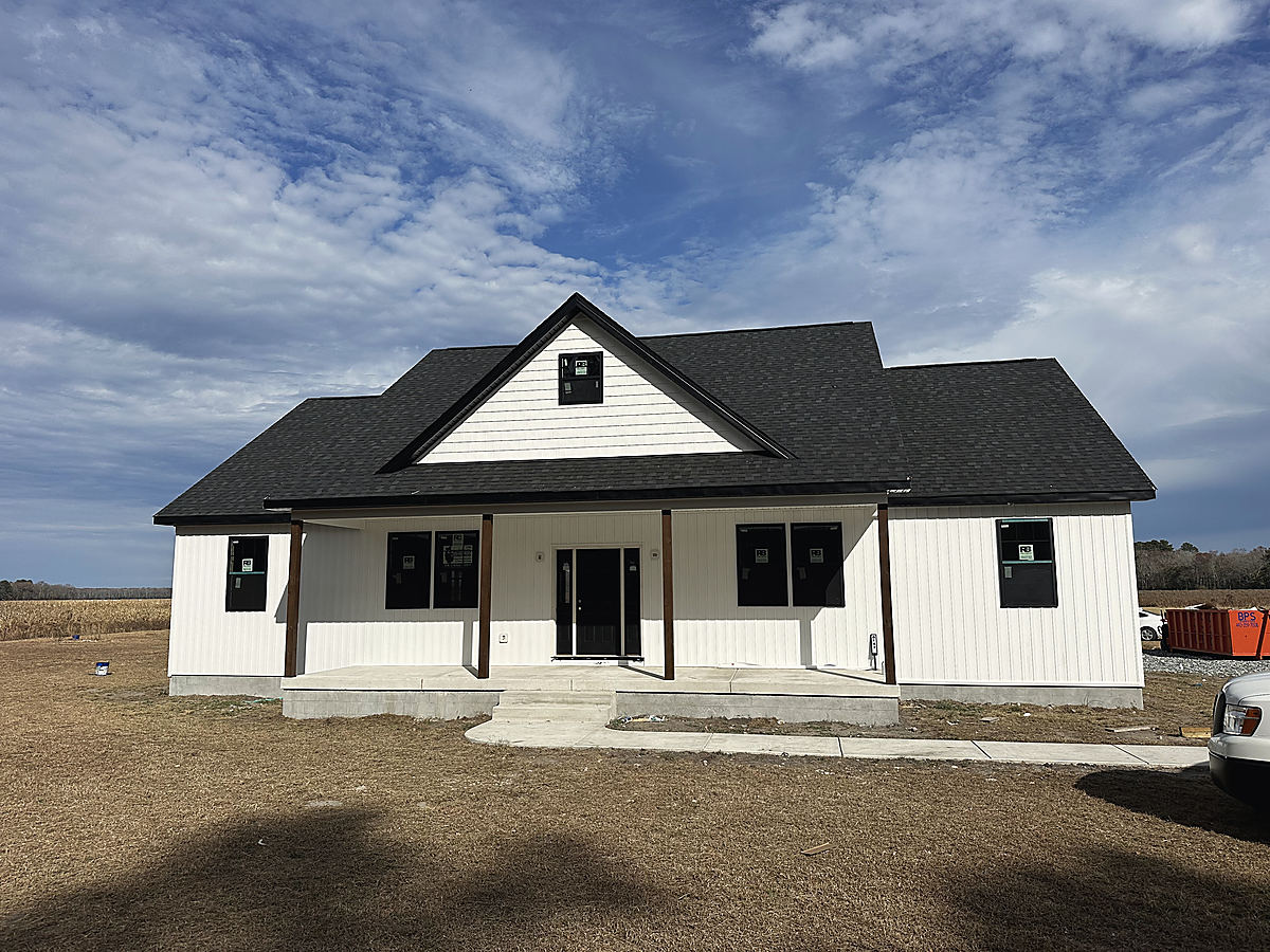 A custom home in Whaleyville: the front of a finished white home with a black roof