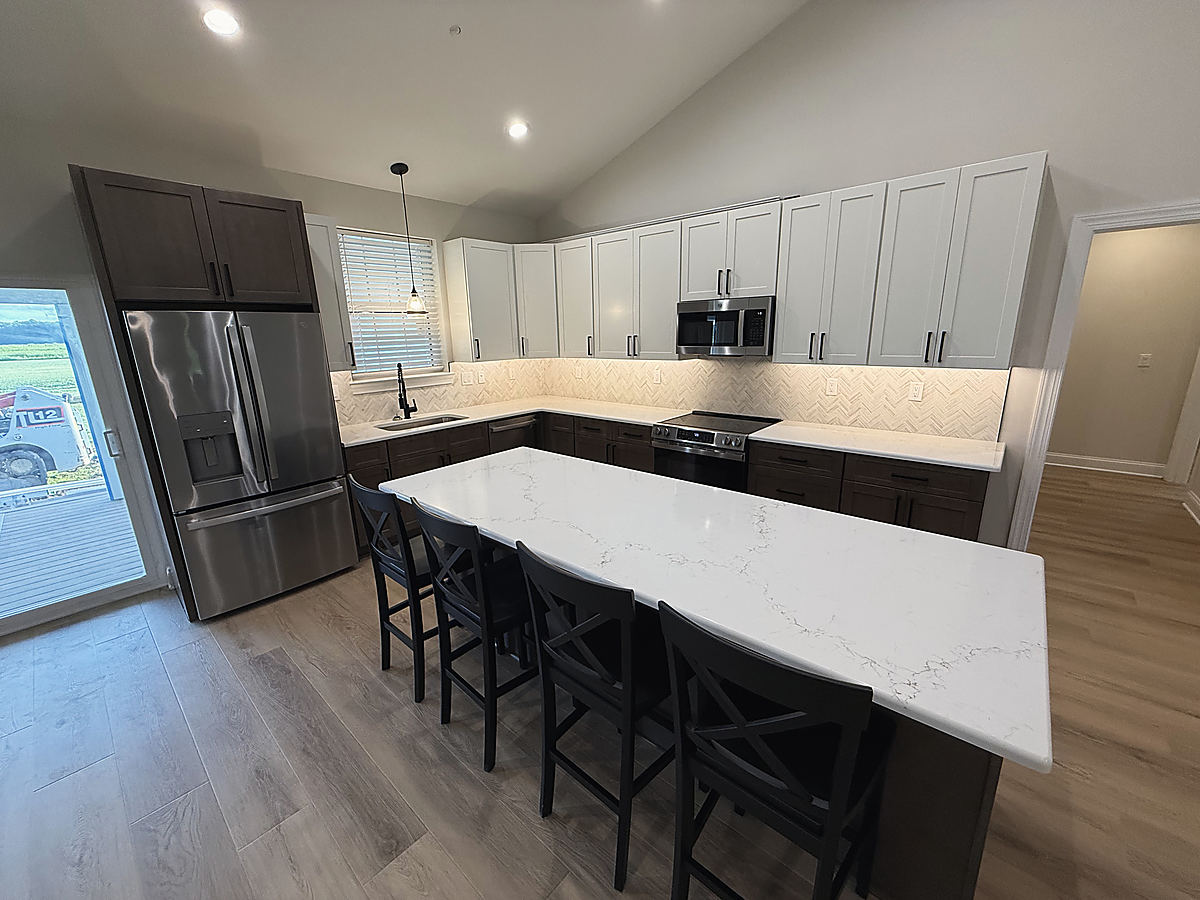 A custom home in Whaleyville: a white kitchen with a large island and stools