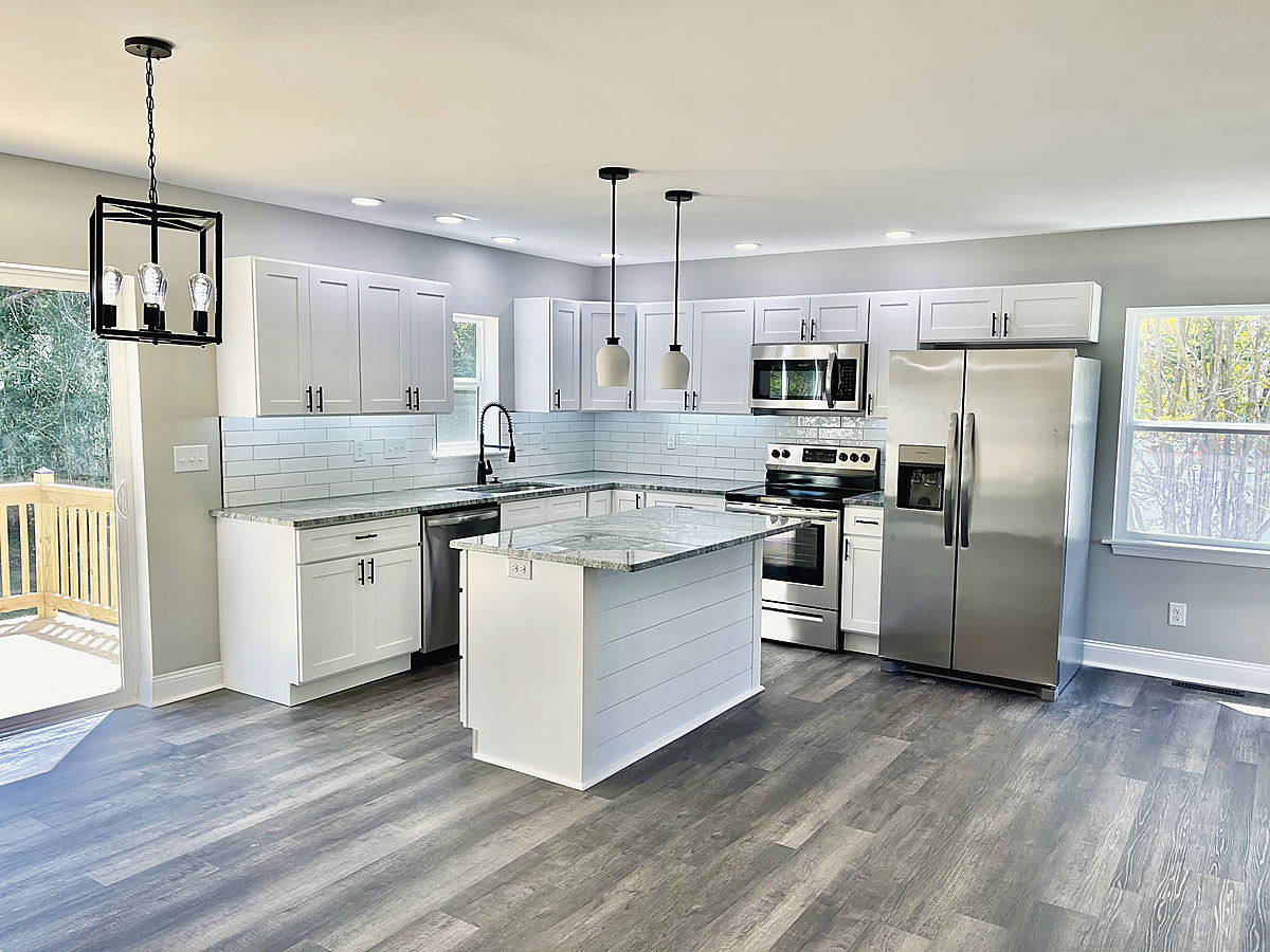 A Del Mar kitchen: a white kitchen with an island, gray floors and black pendant lights