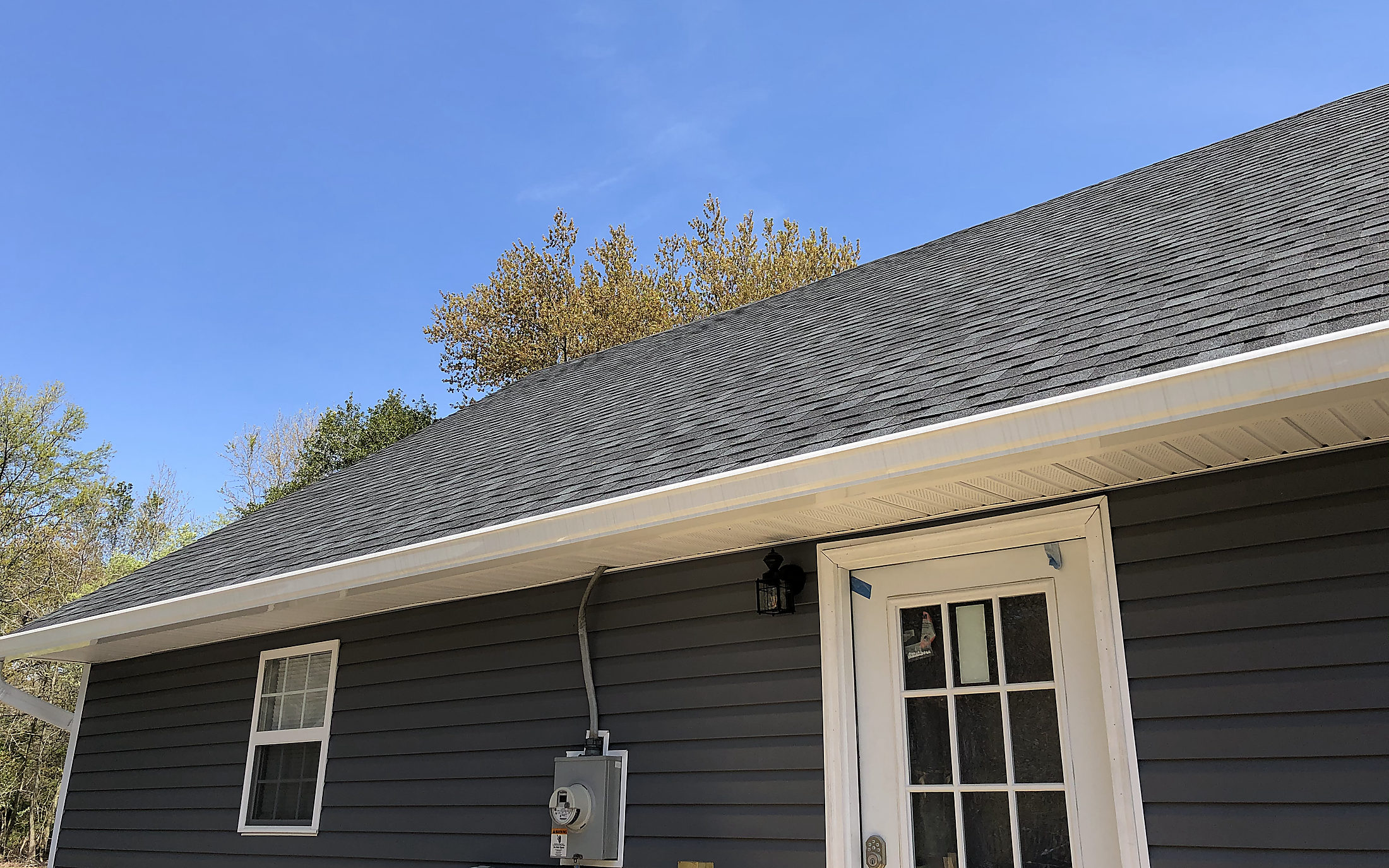 New dark blue vinyl siding with white trim and a new rear door