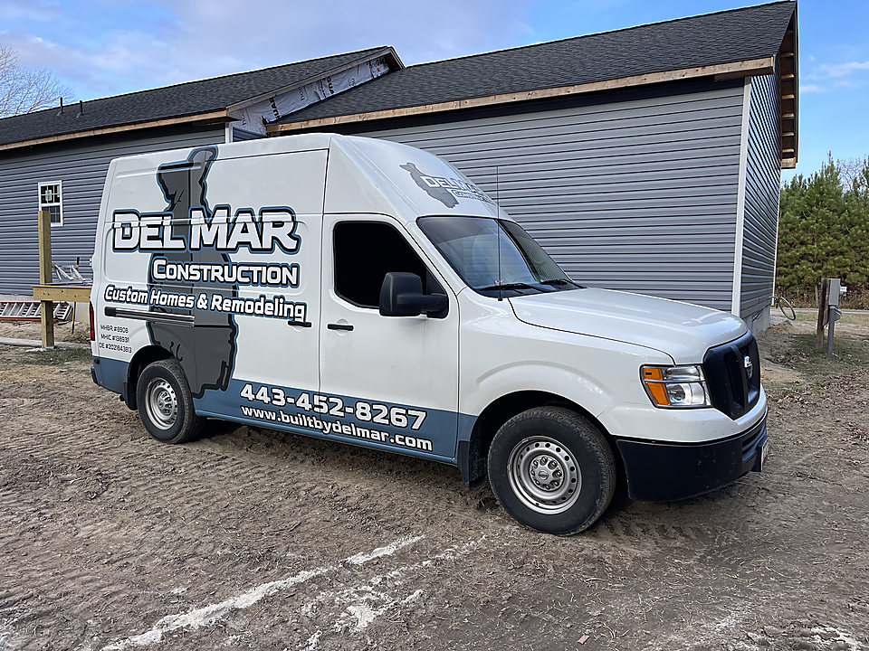 The white Del Mar Construction van with the Delmarva logo and phone number